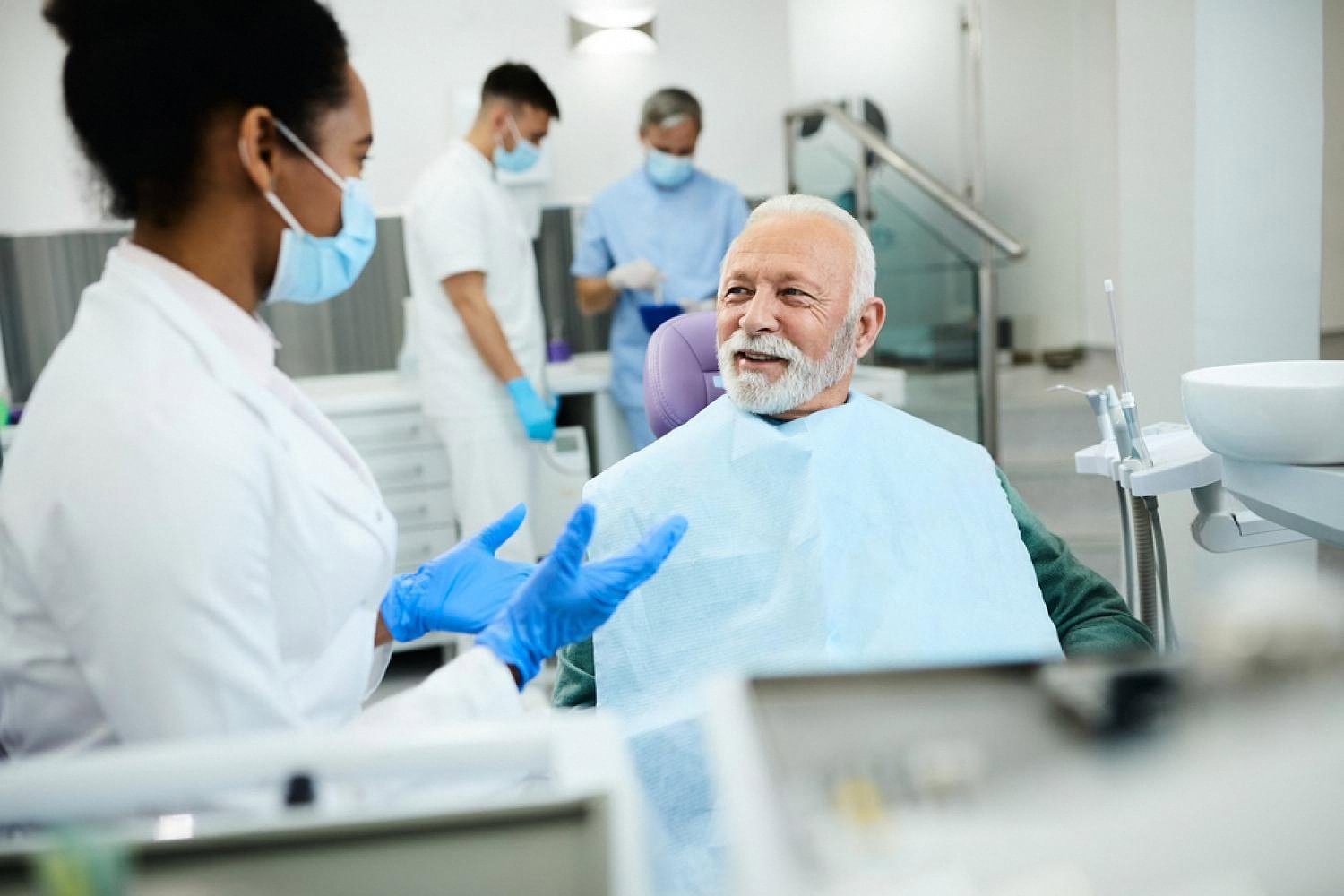 Dental student in white coat treating an older patient in a UAE clinic under supervision